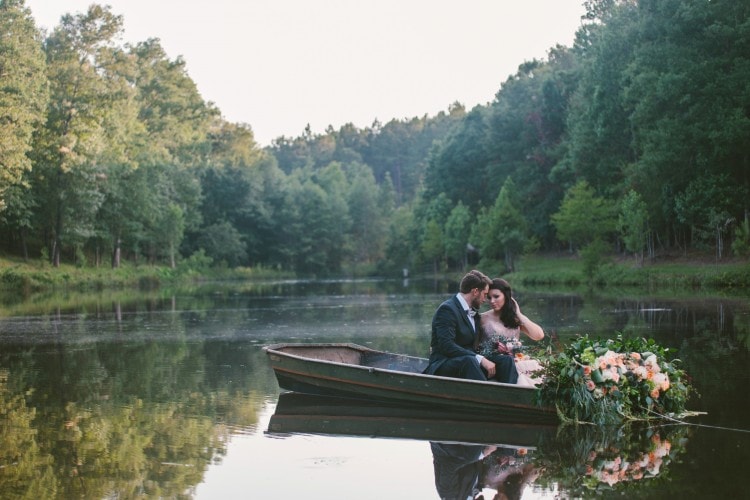 Bride and Groom portrait in boat on lake, pine trees in background - by Starling & Sage Hattiesburg, MS Wedding Photographers